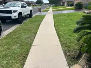 Long stretch of freshly edged sidewalk bordered by neatly mowed lawns in a residential neighborhood